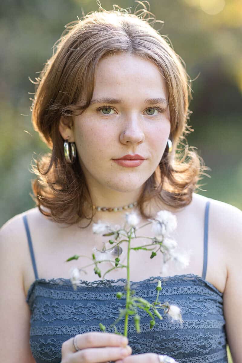 Teenage girl in blue dress holds flower