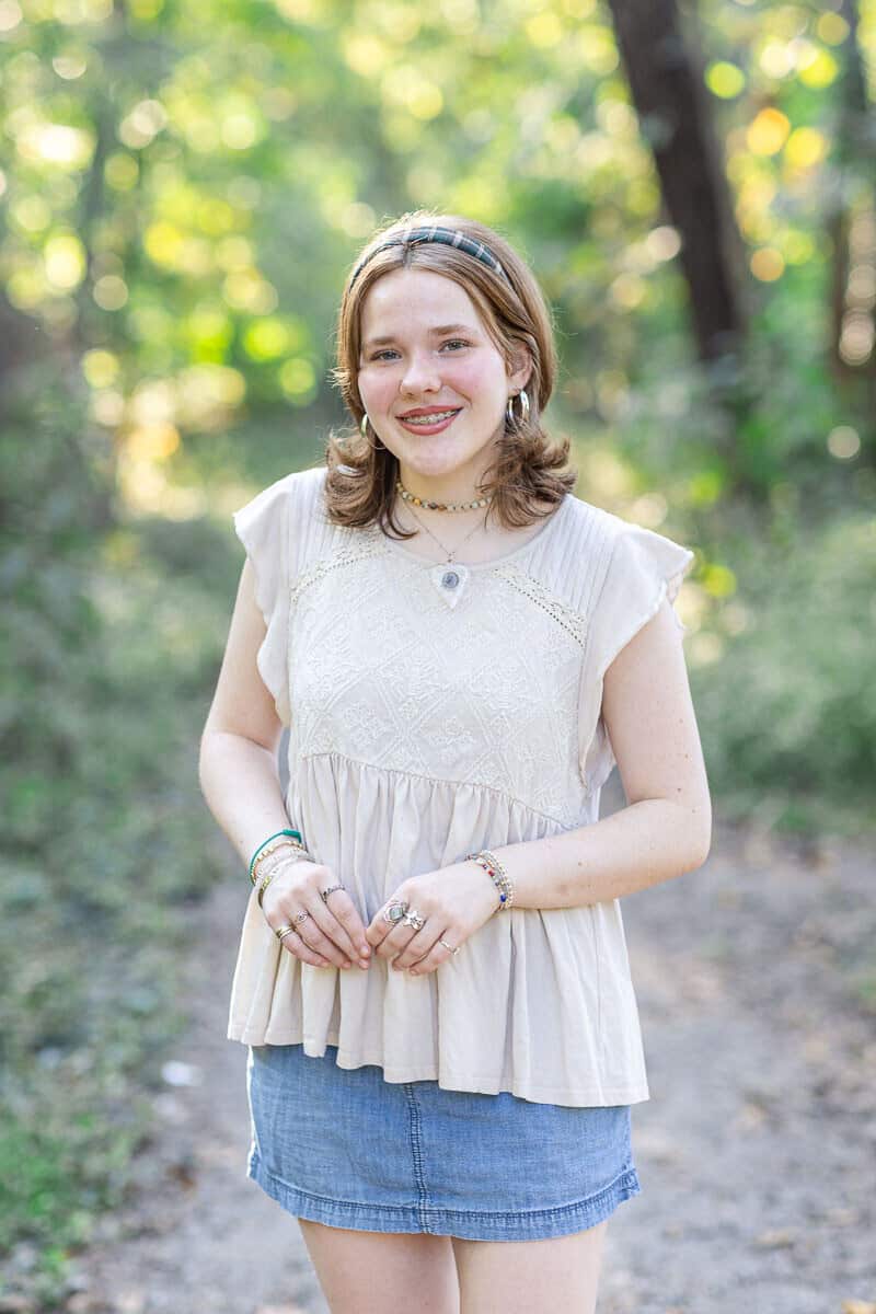 teenage girl poses in woods with denim skirt