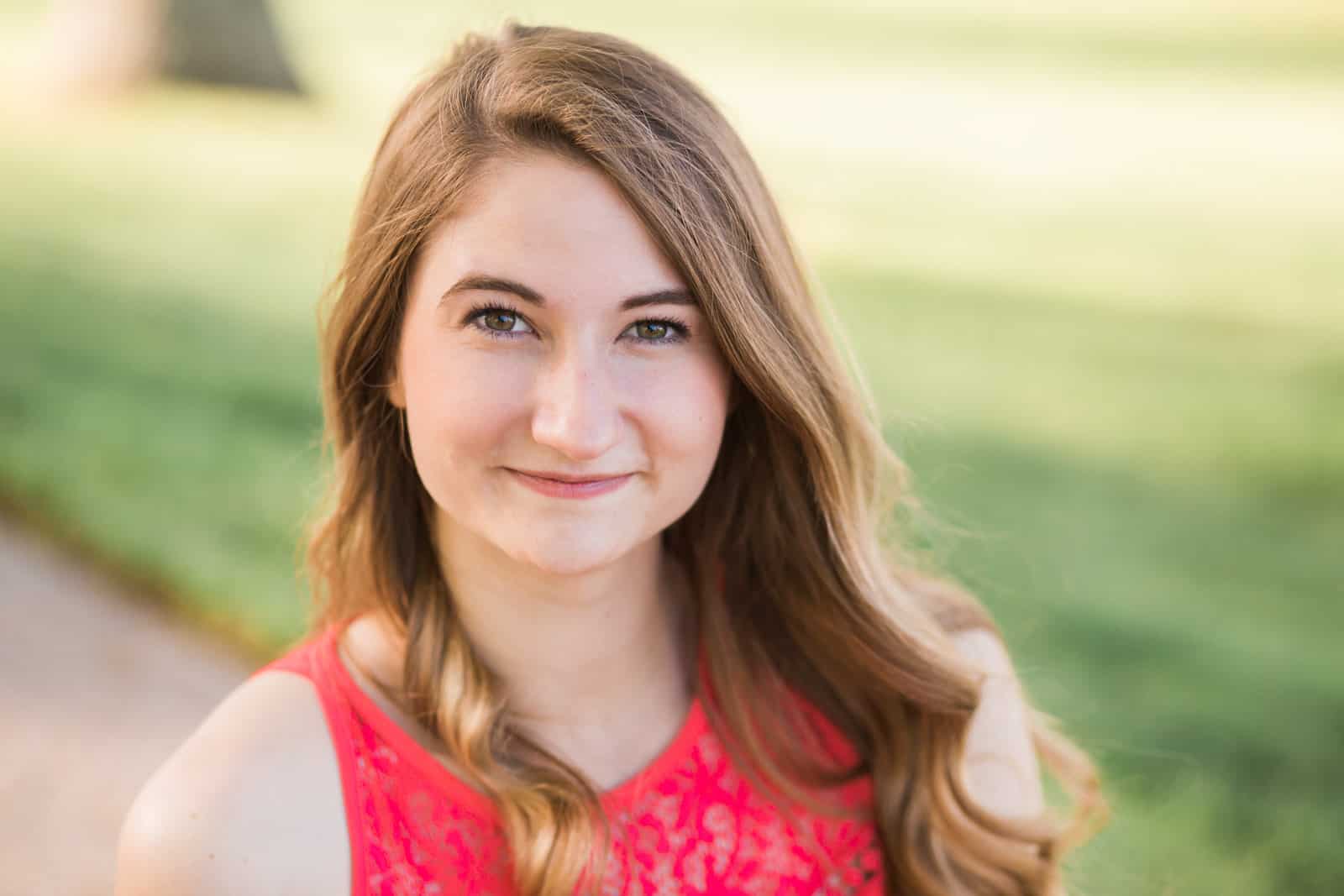 senior teenage girl portrait outside in sun with bright pink dress