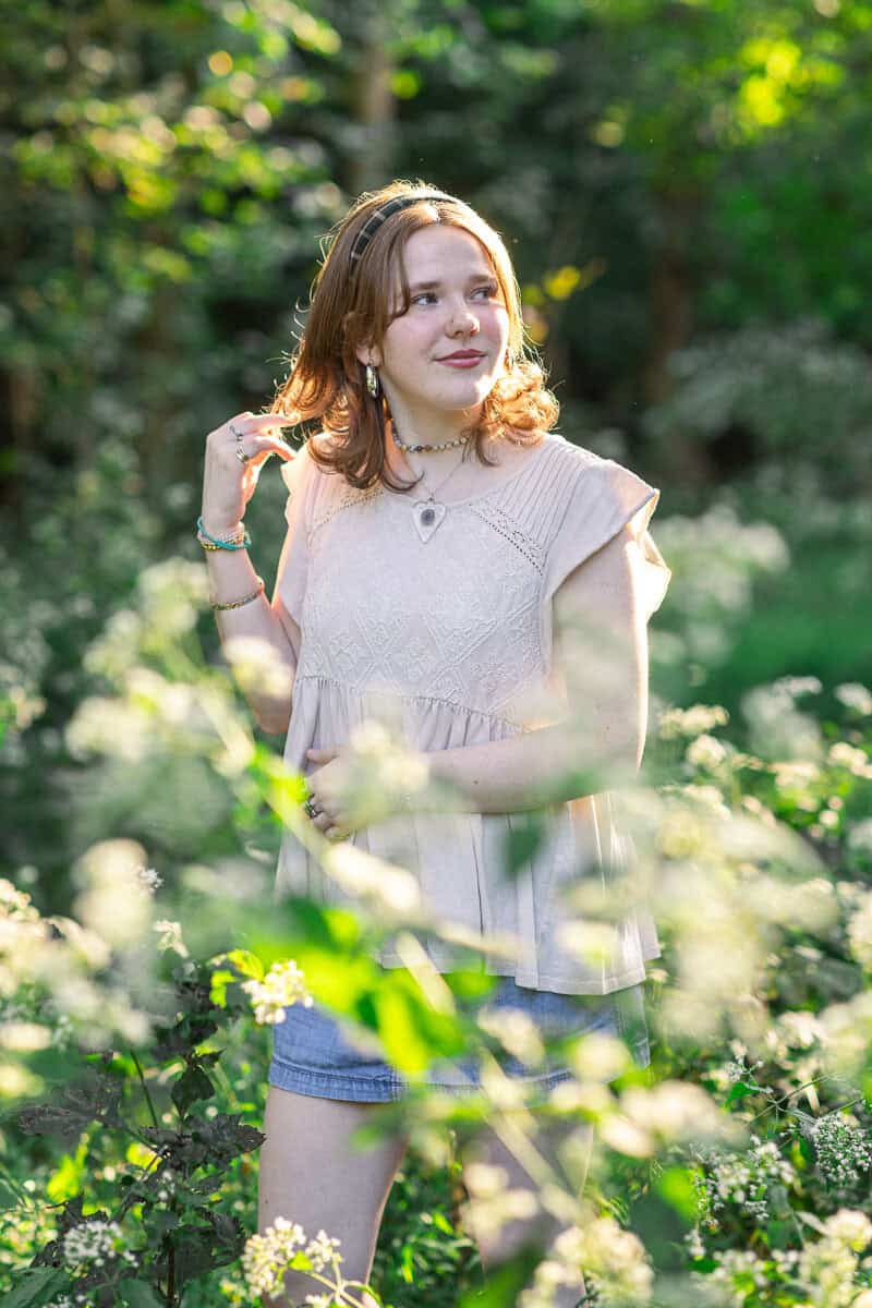 teenage girl poses in woods with soft sunlight