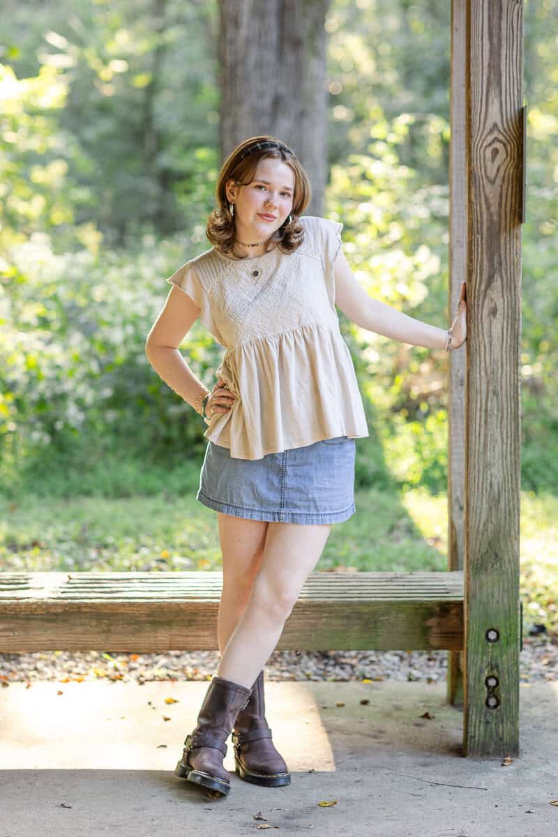 teenage girl in denim skirt poses in wooded area