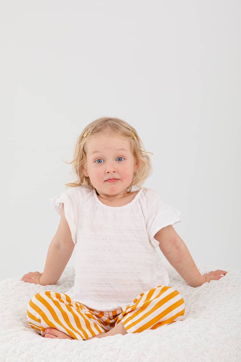 Toddler girl with blond curly hair makes surprise face
