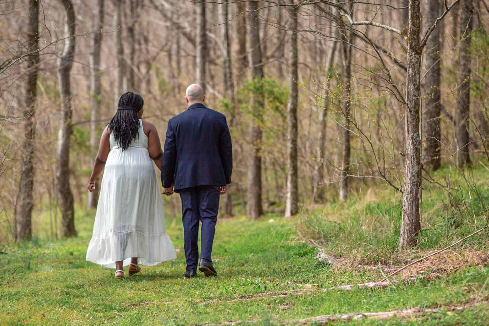 Spring Nashville Elopement at Butterfly Hollow; bride and groom walk through the woods shown from the back