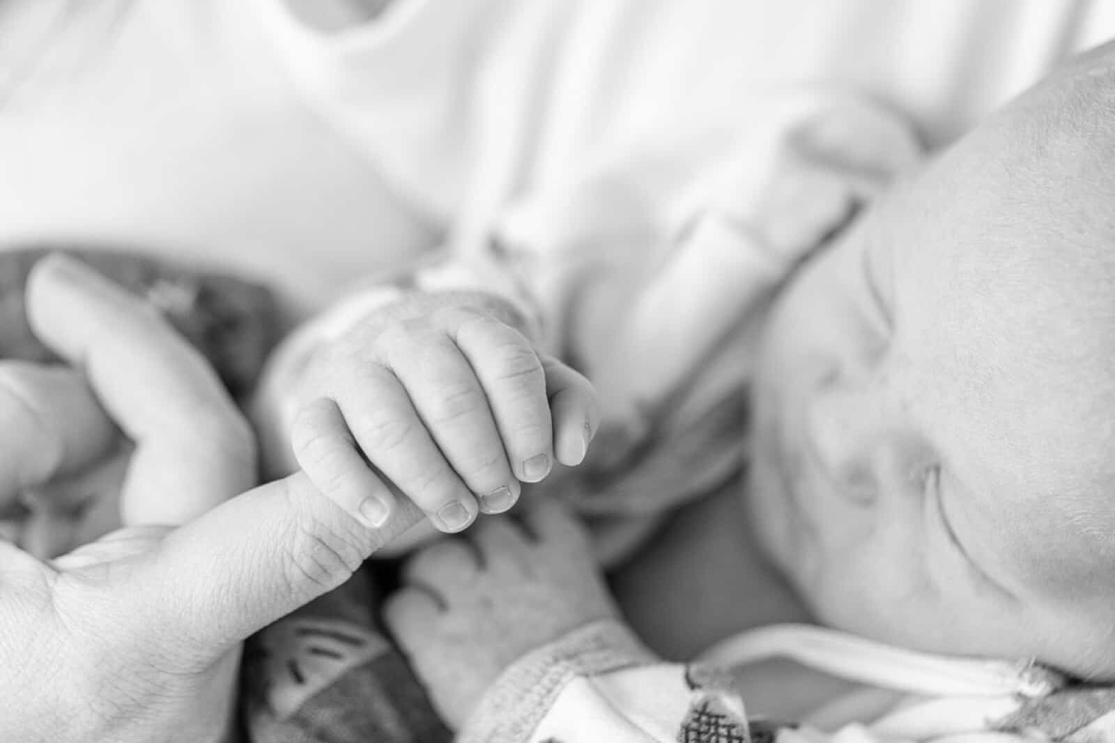 newborn baby holds on to mothers finger