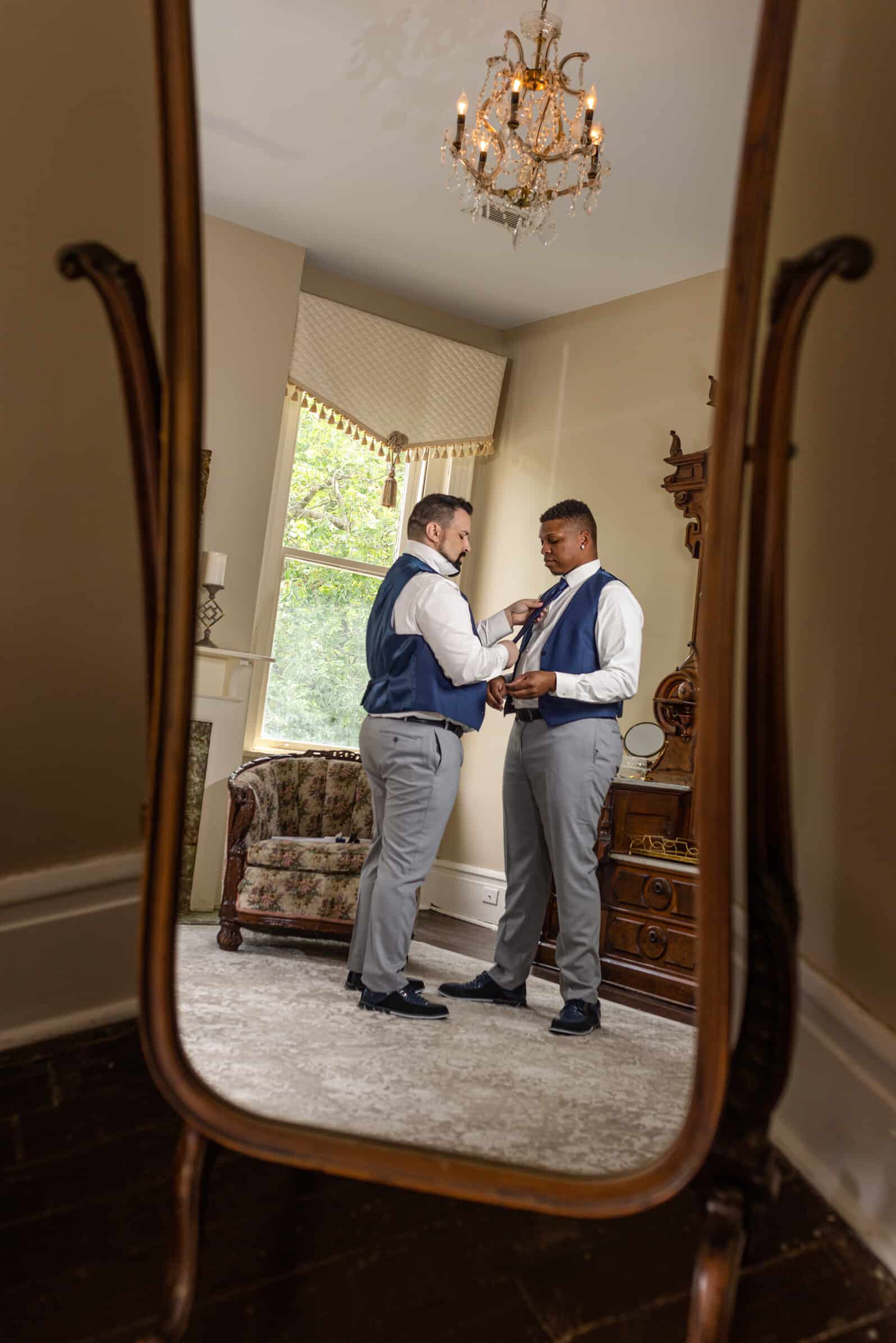Same sex couple get dressed and ready for their wedding, image in full length mirror