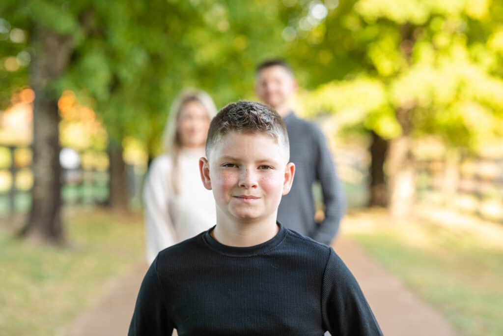 Close up of 10 year old boy with parents blurred in background