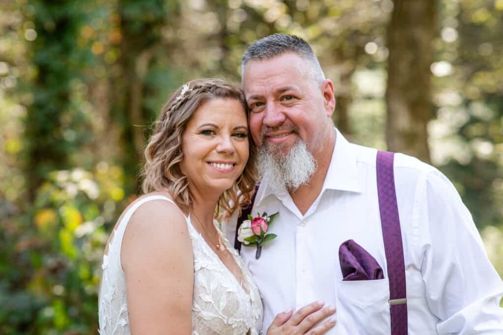 middle aged elopement couple smile with woods in background