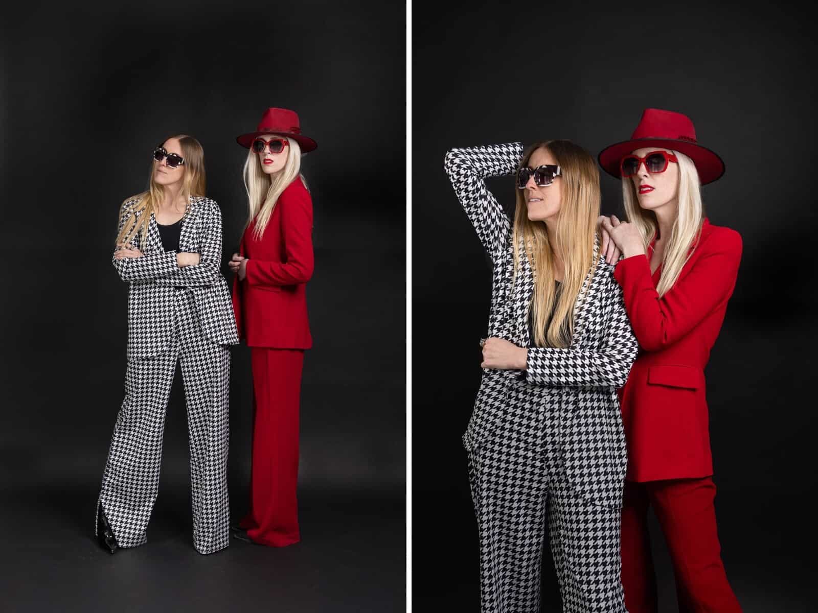 two models in pantsuits with hats and sunglasses against black background