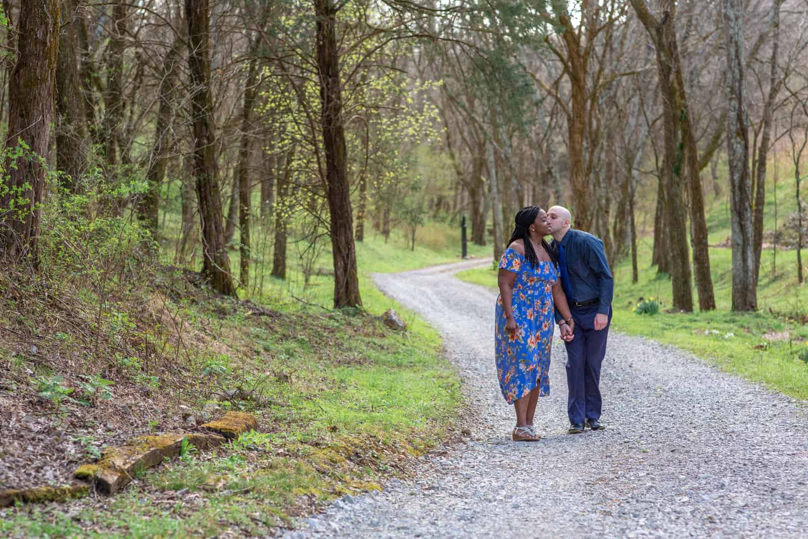 Spring Nashville Elopement at Butterfly Hollow; bride and groom walk down winding gravel drive with woods all around