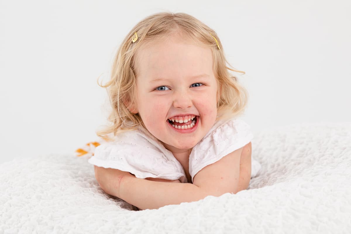 Blond toddler girl giggling in studio portrait