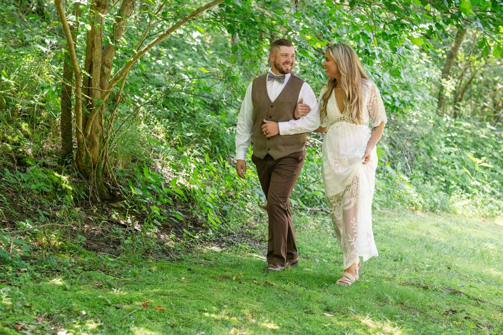 bride and groom walk through sunny woods