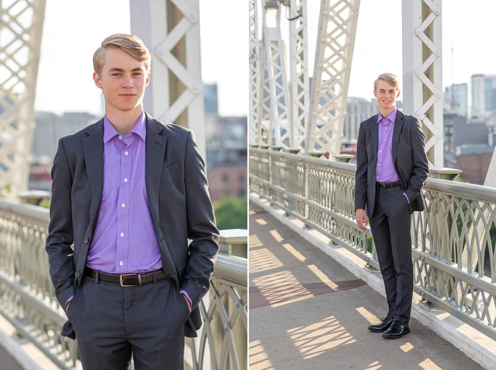 Senior boy with blond hair poses for portraits in gray suit and purple shirt on bridge