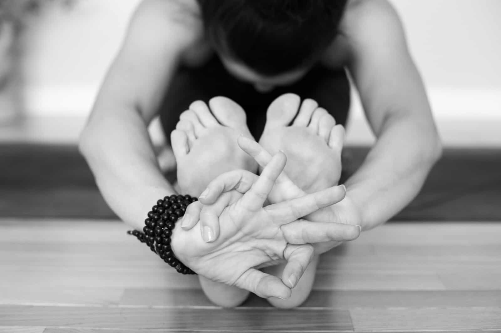 Close up of yoga teacher hands and feet in hand mudra in black & white