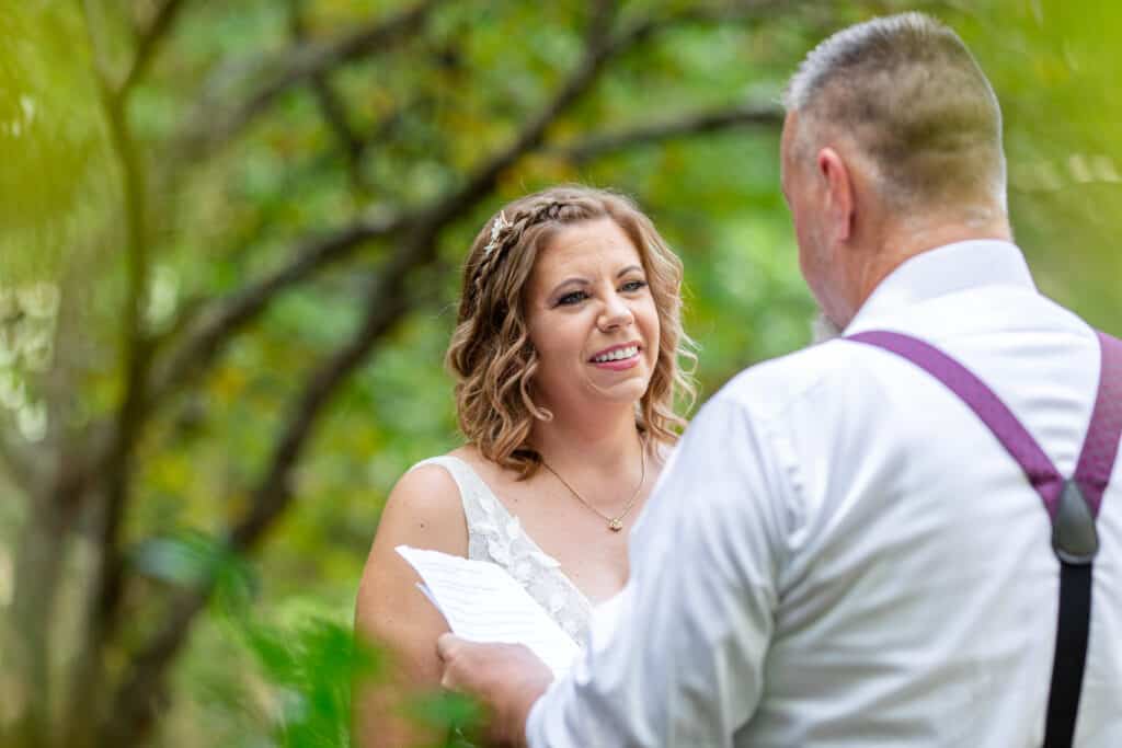 groom reads his vows in woods
