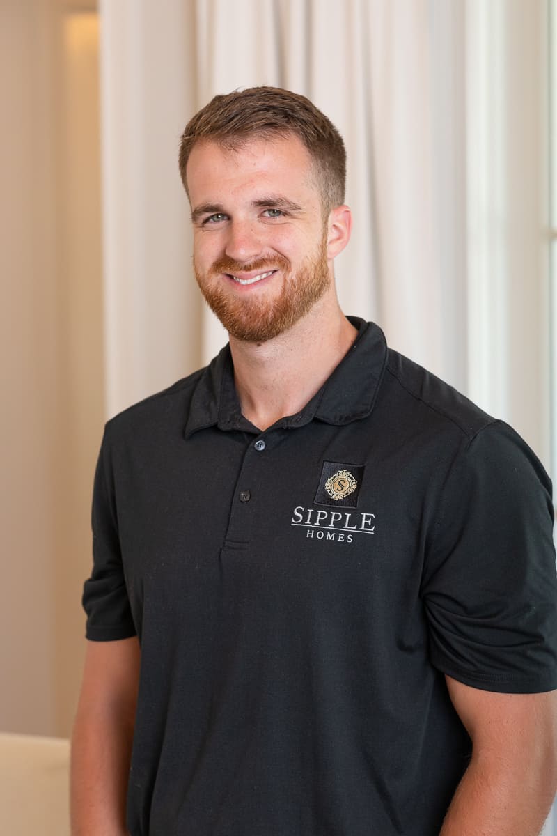 Home builder with black polo shirt poses for headshot inside residence.