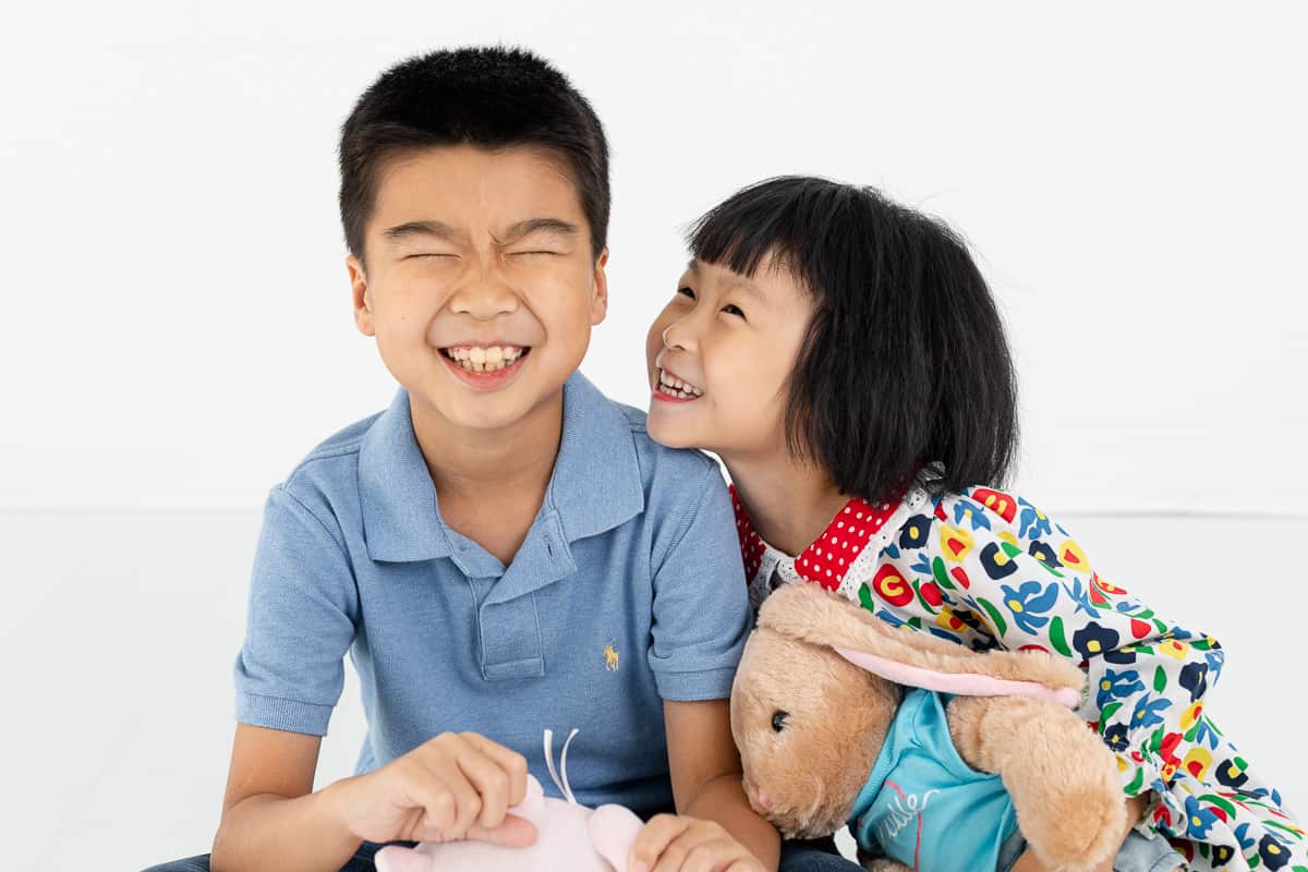 brother and sister giggling in studio portrait session