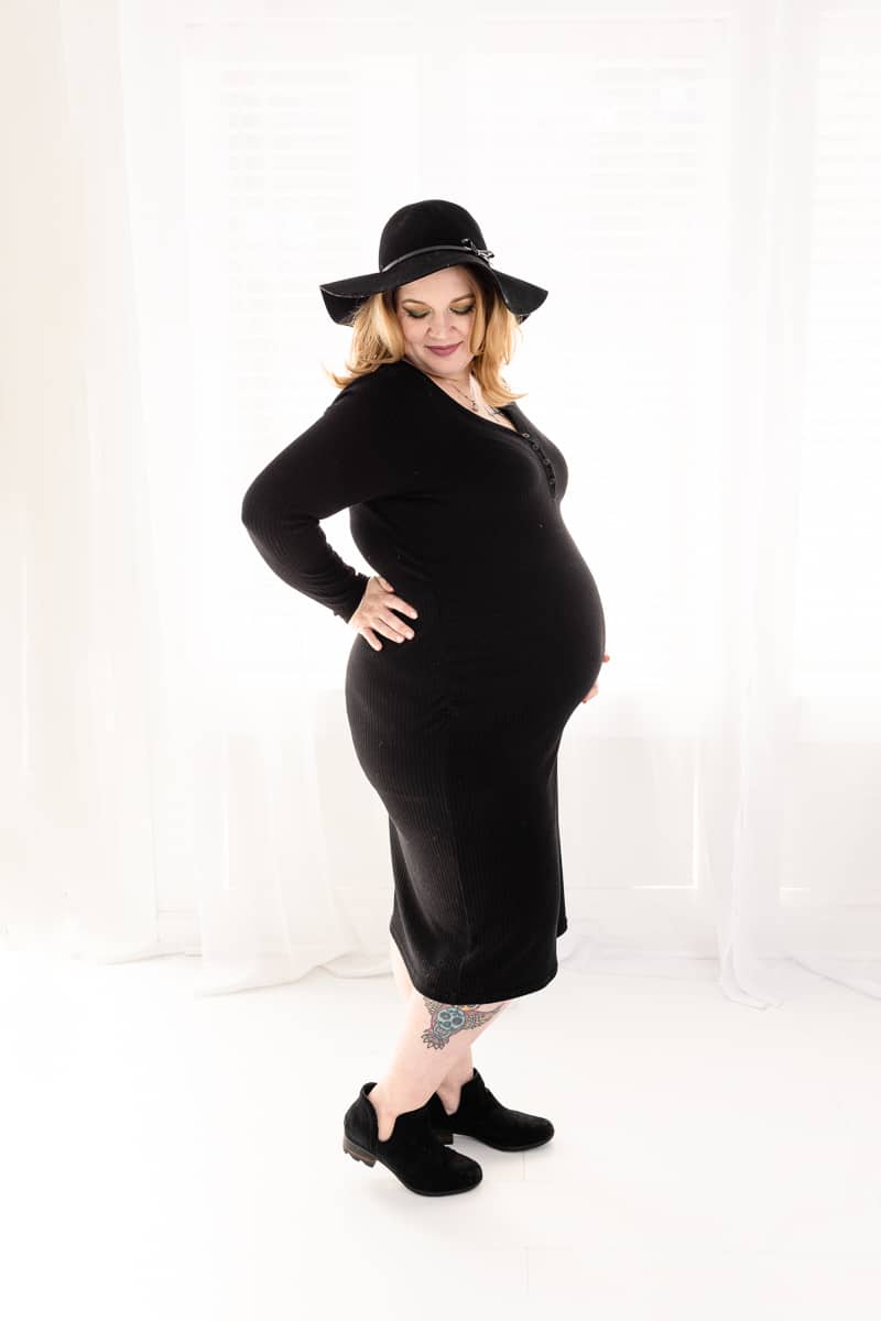 pregnant woman in black dress, hat and short boots sillouetted